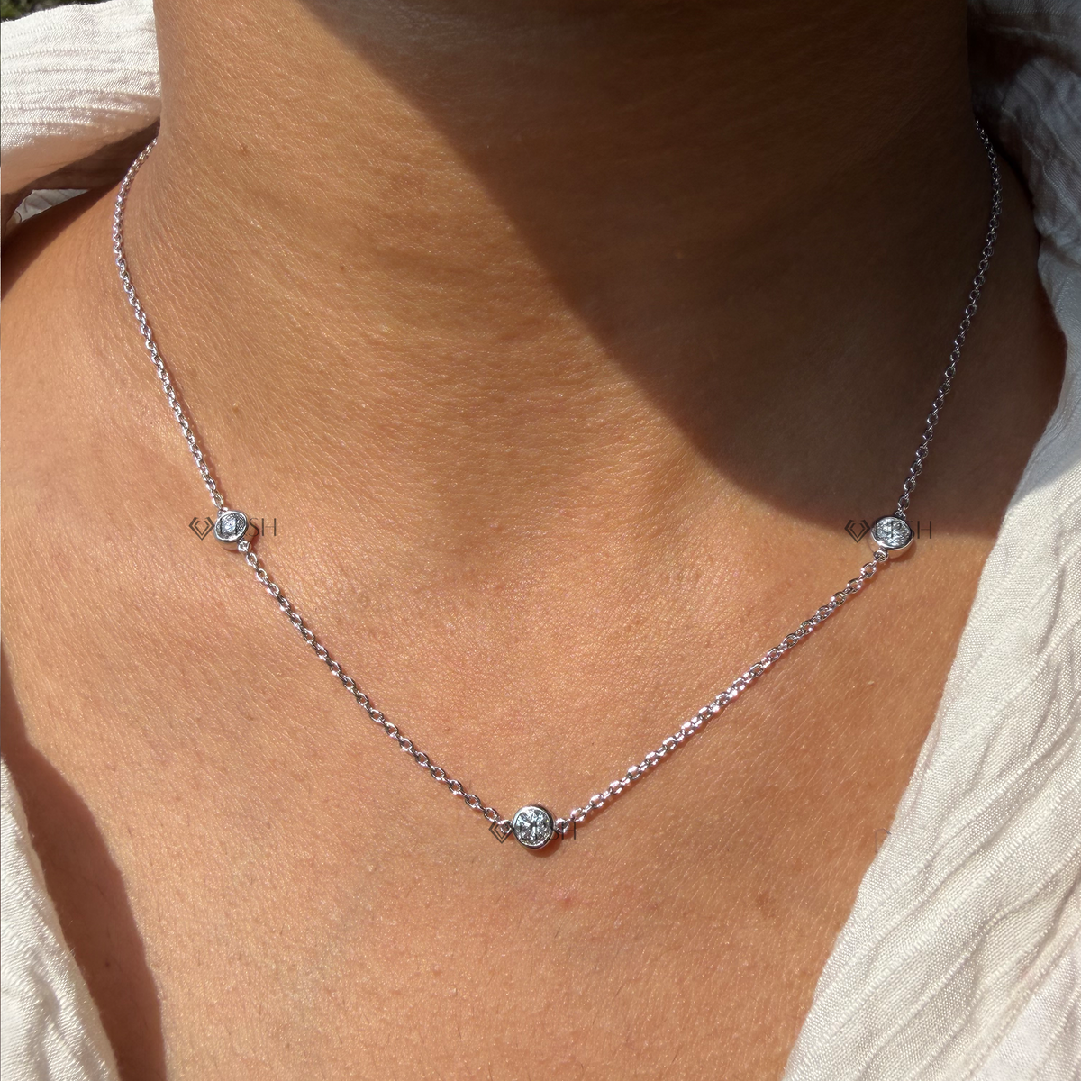 Daylight perspective of white gold three stone diamond station cable chain worn on neck