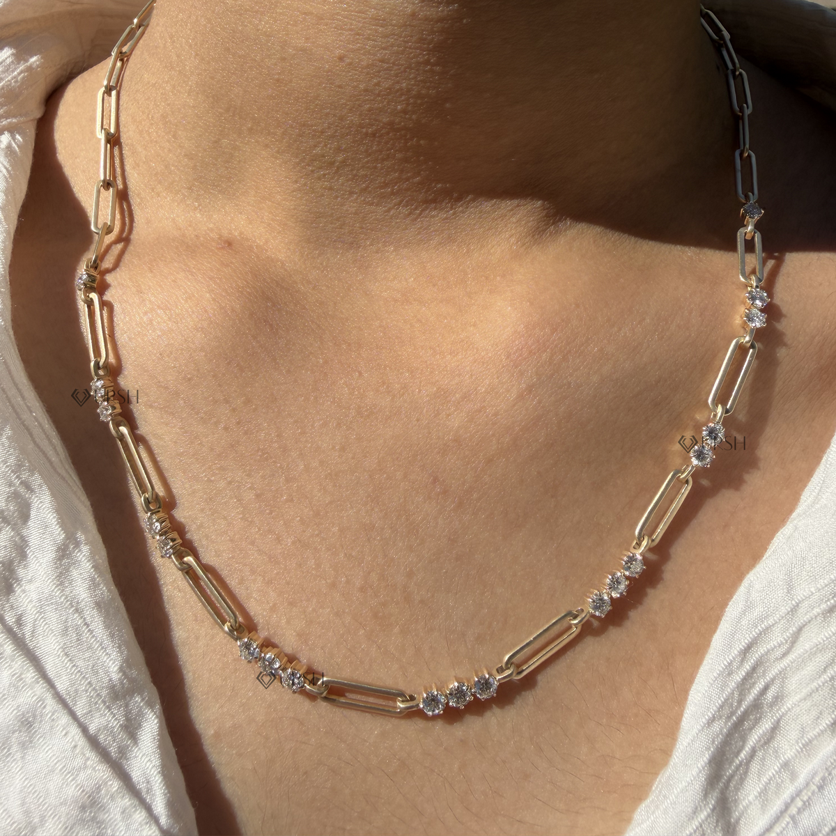 Yellow gold alternating diamond station paperclip link necklace styled gracefully on neck in natural daylight
