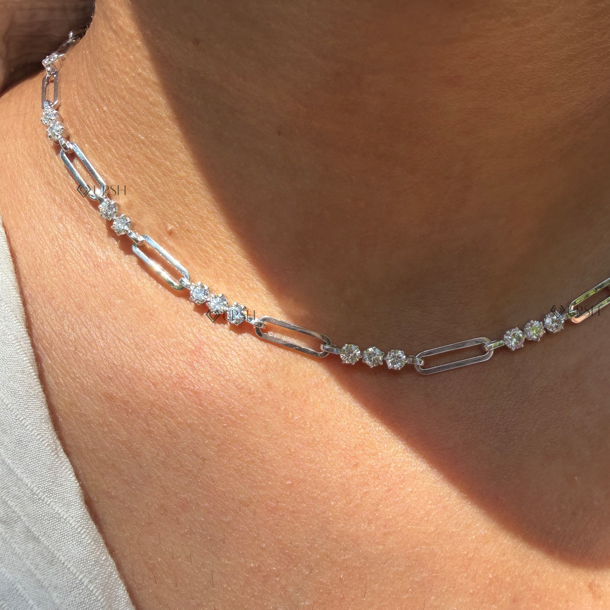 Daylight perspective of white gold alternating diamond station paperclip chain worn on neck