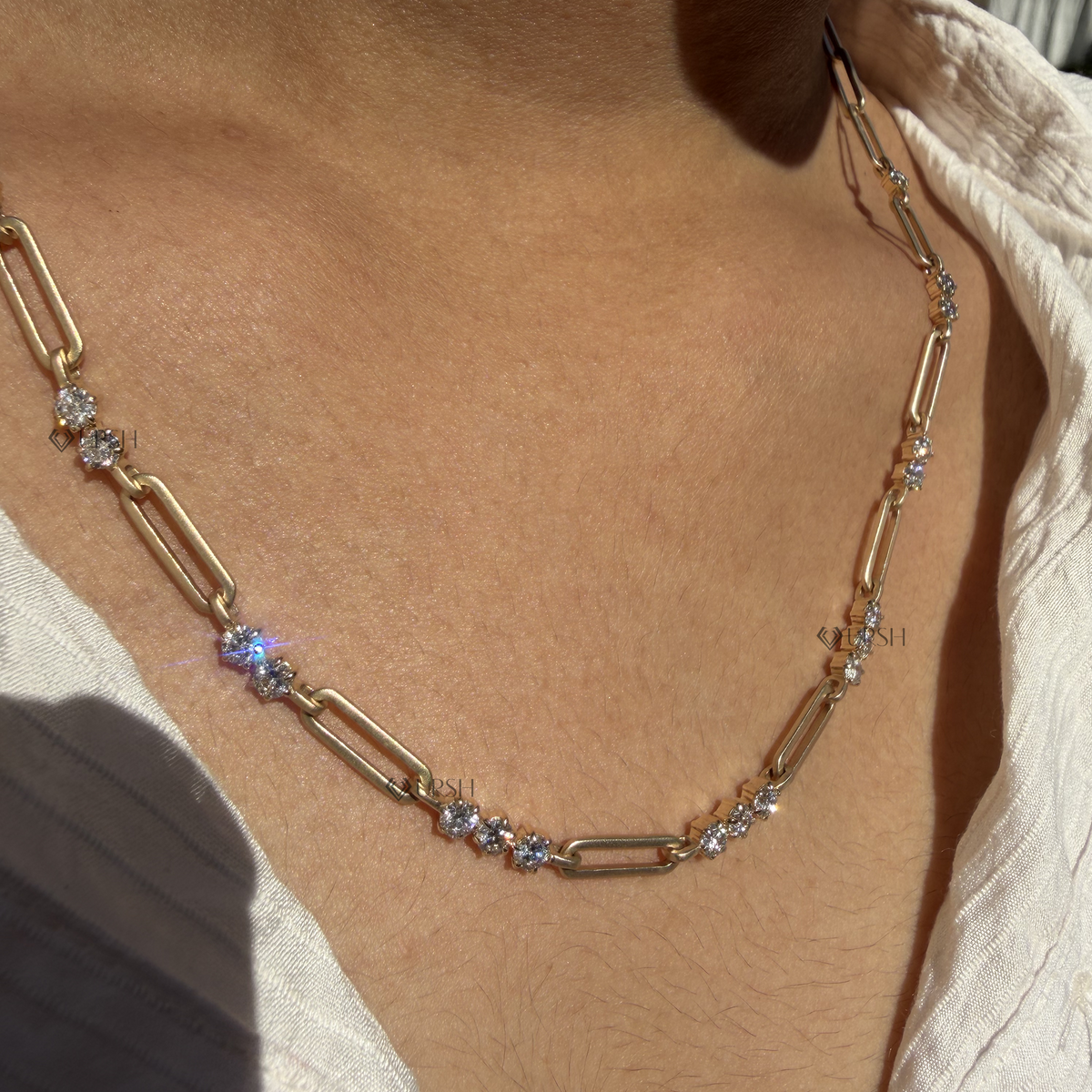 Daylight angle view of yellow gold diamond station paperclip chain necklace worn on collarbone