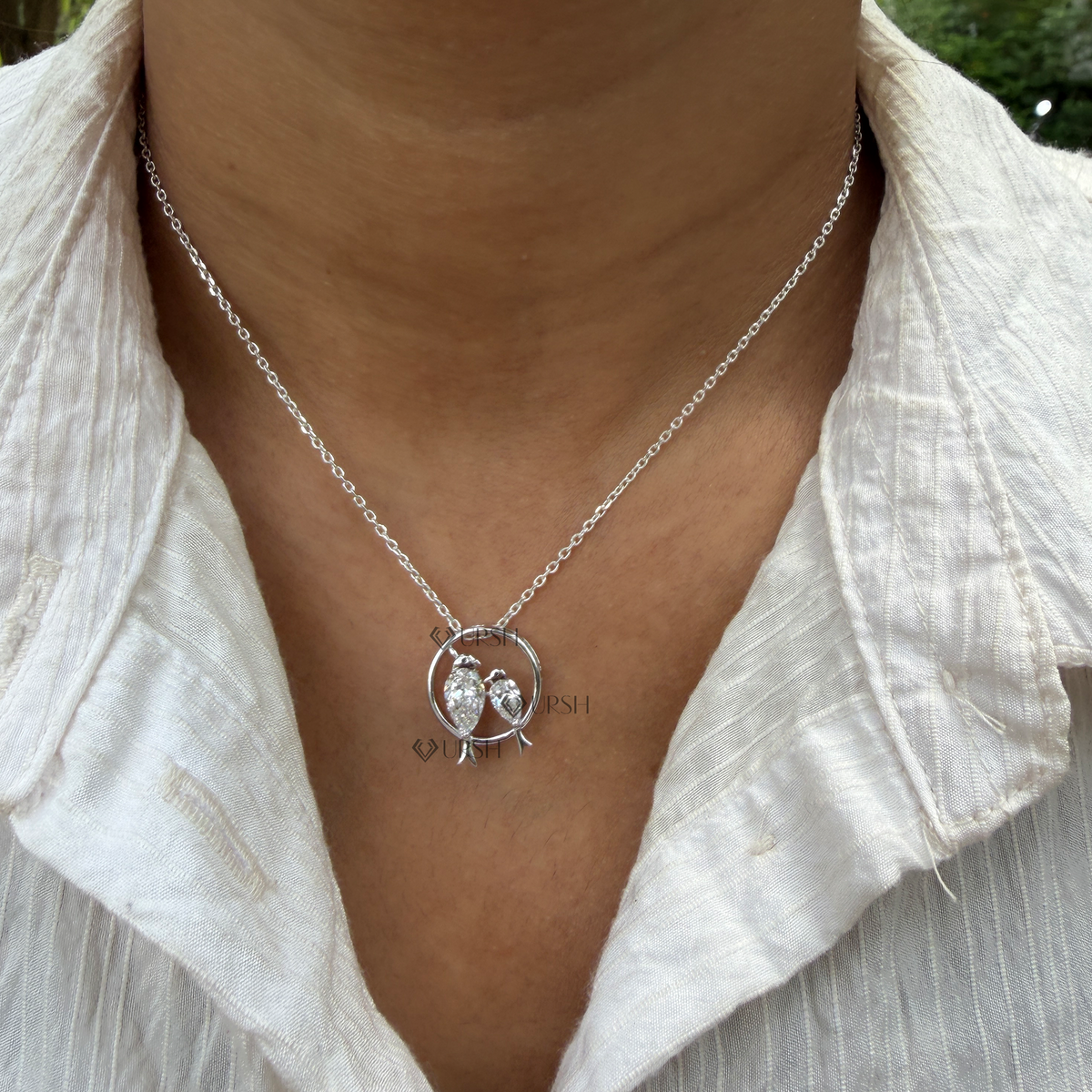 Daylight perspective view of white gold love birds pear cut diamond pendant necklace worn on neck