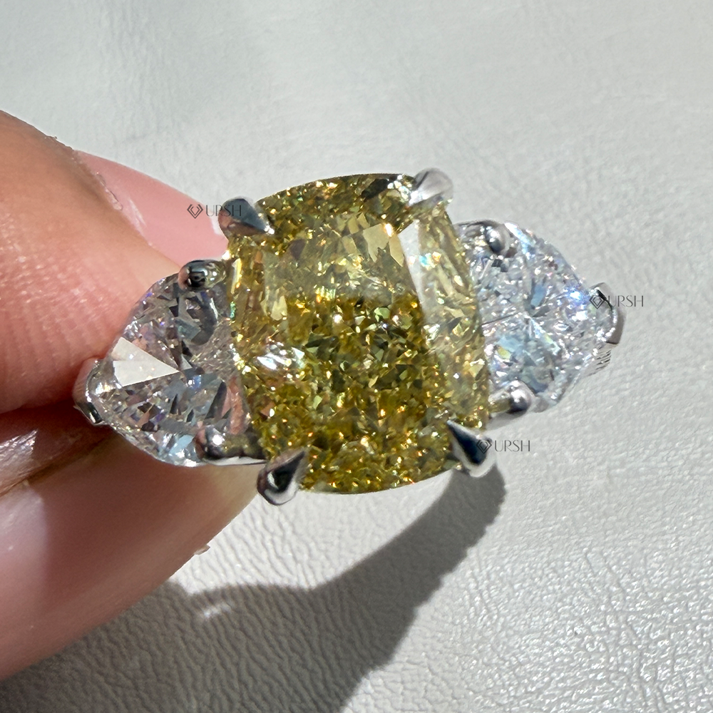 Holding two-tone yellow cushion diamond ring showcasing side heart stone brilliance and shoulder pavé