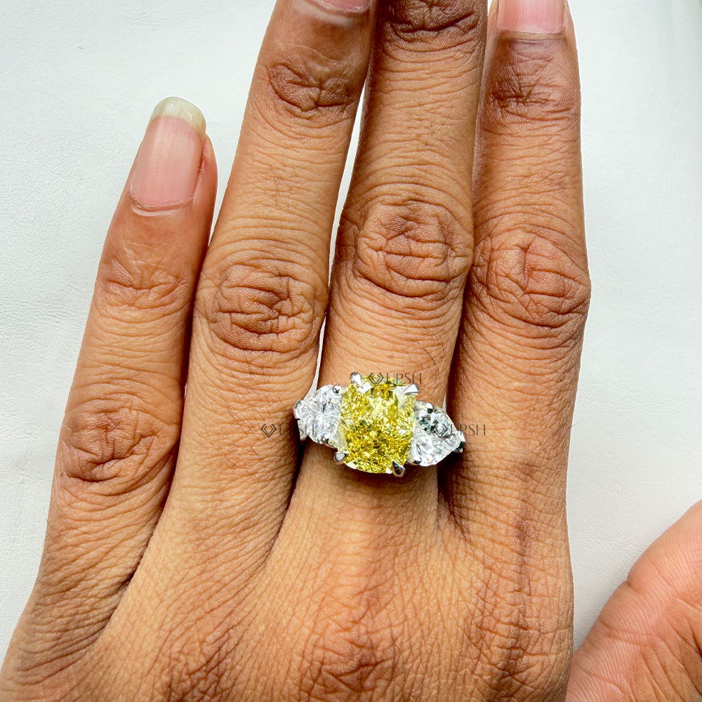 Close-up holding solid gold yellow cushion trilogy ring displaying corner prongs and heart facet fire
