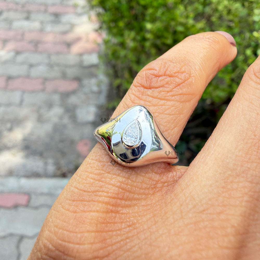 Sculpted white gold pear diamond signet ring worn on index finger in natural daylight