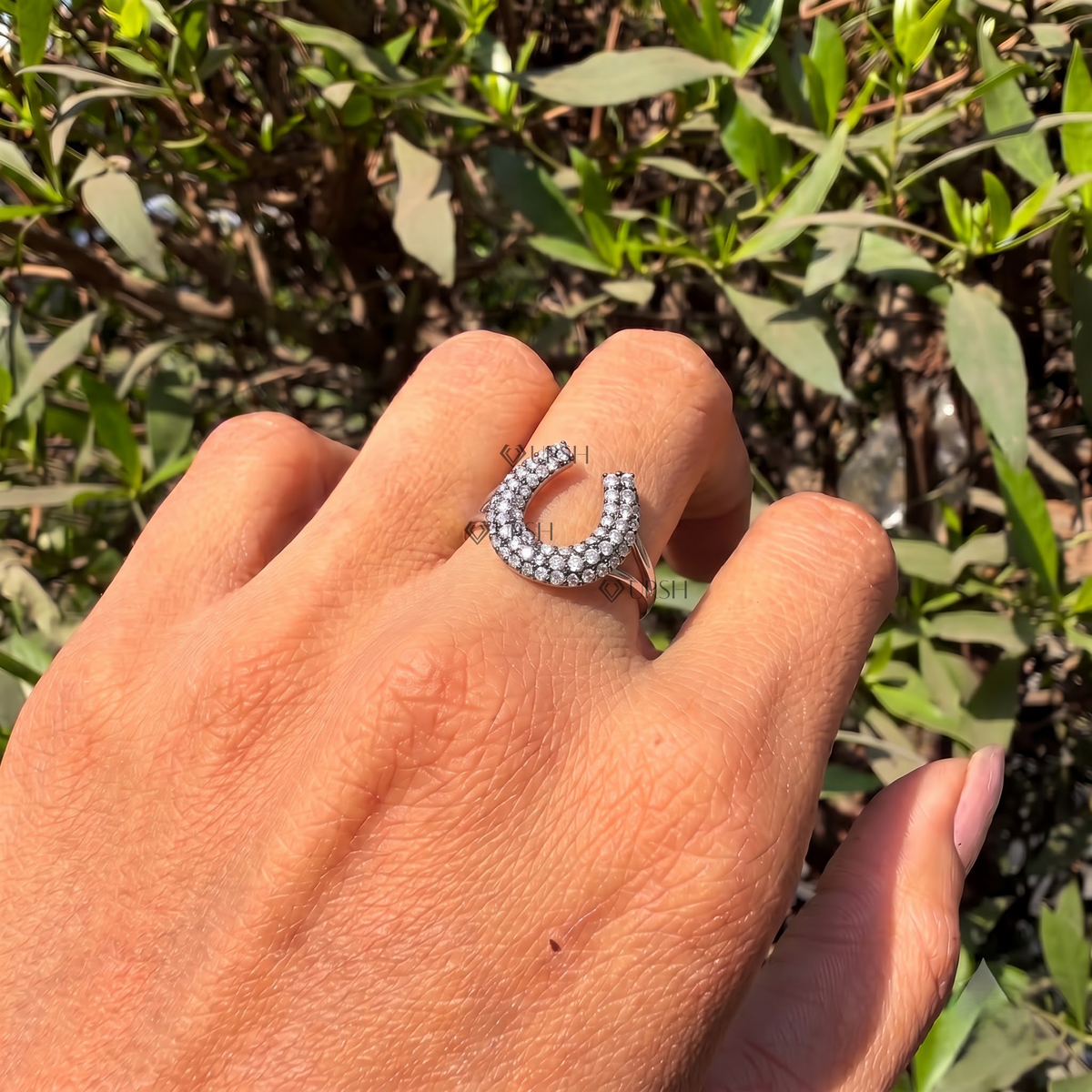 Equestrian pavé horseshoe ring catching bright natural light on finger