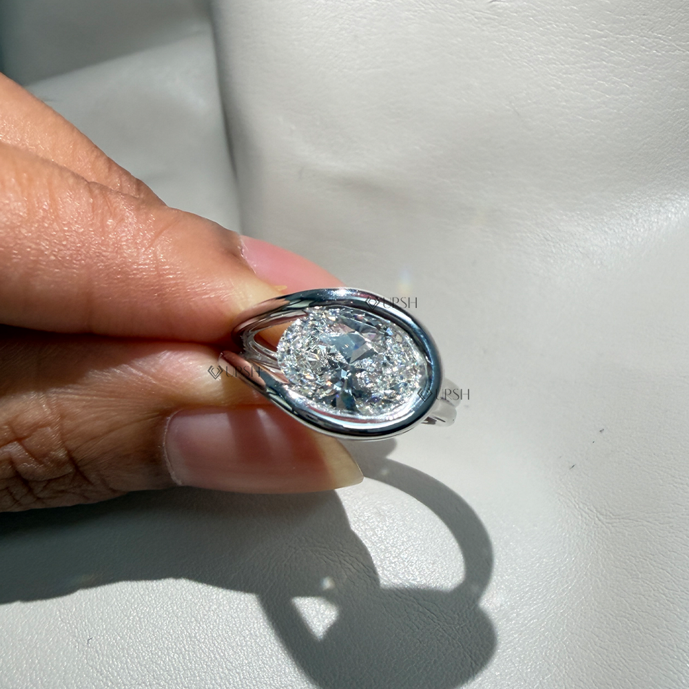 Close-up holding solid gold east-west oval bypass ring highlighting open negative space design