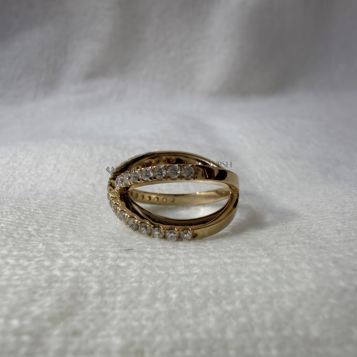 Studio view of yellow gold criss-cross band showing intertwined profile and smooth inner shank