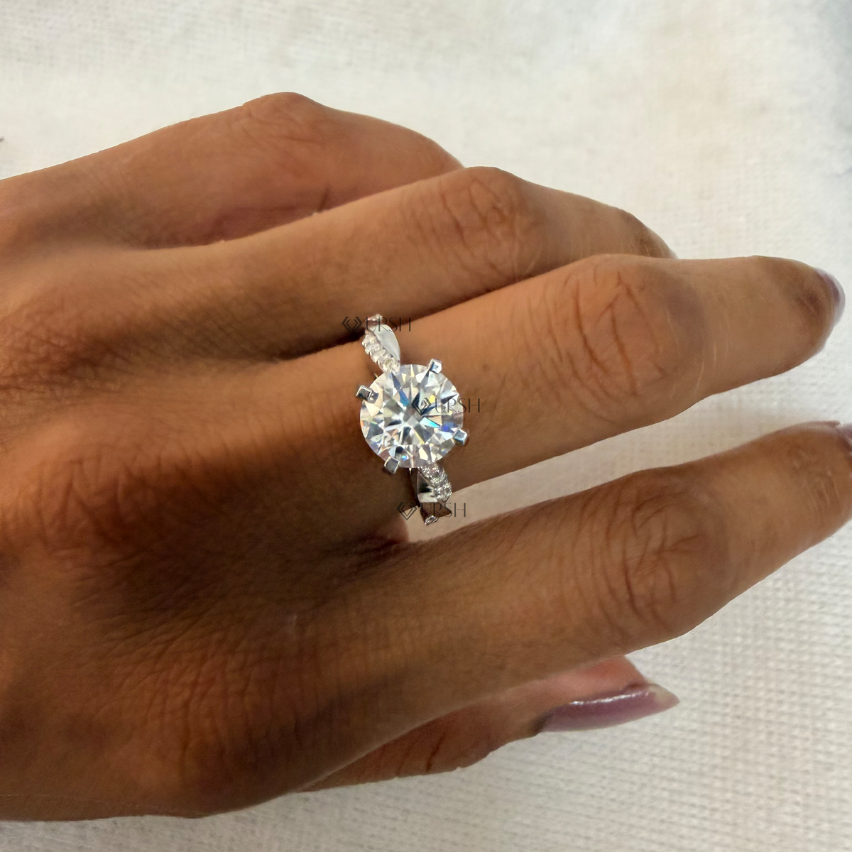Yellow gold twist band engagement ring worn against natural garden greenery