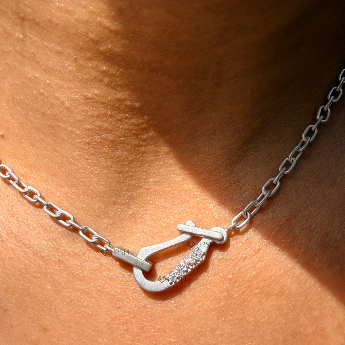 Daylight angle view of white gold diamond accent carabiner lock centerpiece and paperclip chain worn on neck