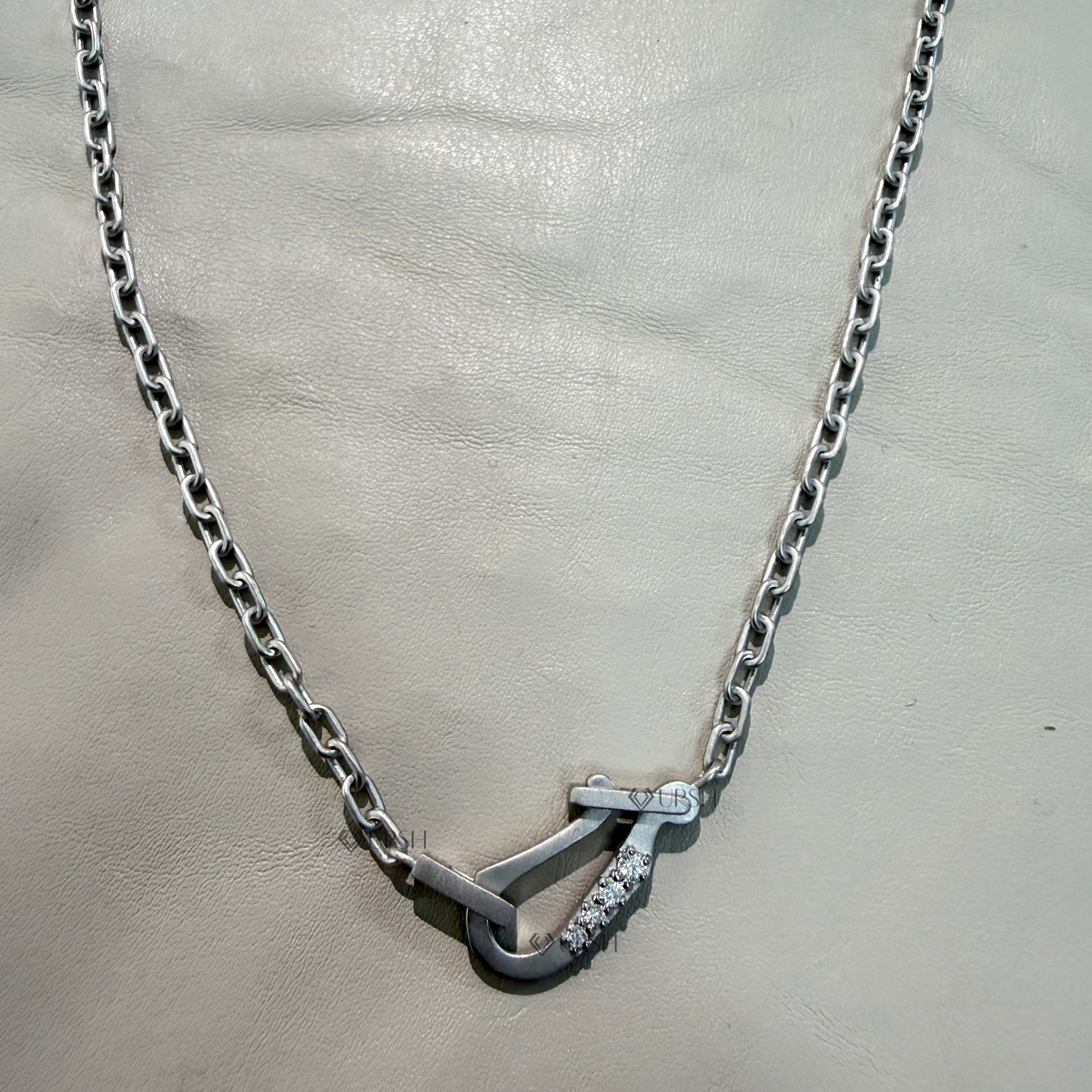 Solid white gold carabiner hook diamond paperclip chain necklace laid flat on presentation background
