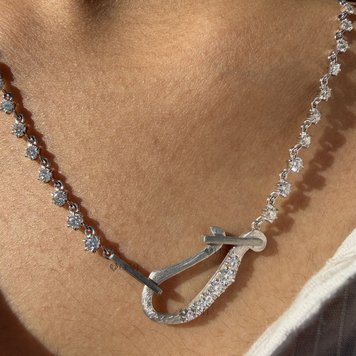 Daylight macro view of white gold pavé diamond carabiner lock centerpiece and graduated diamond stations worn on neck