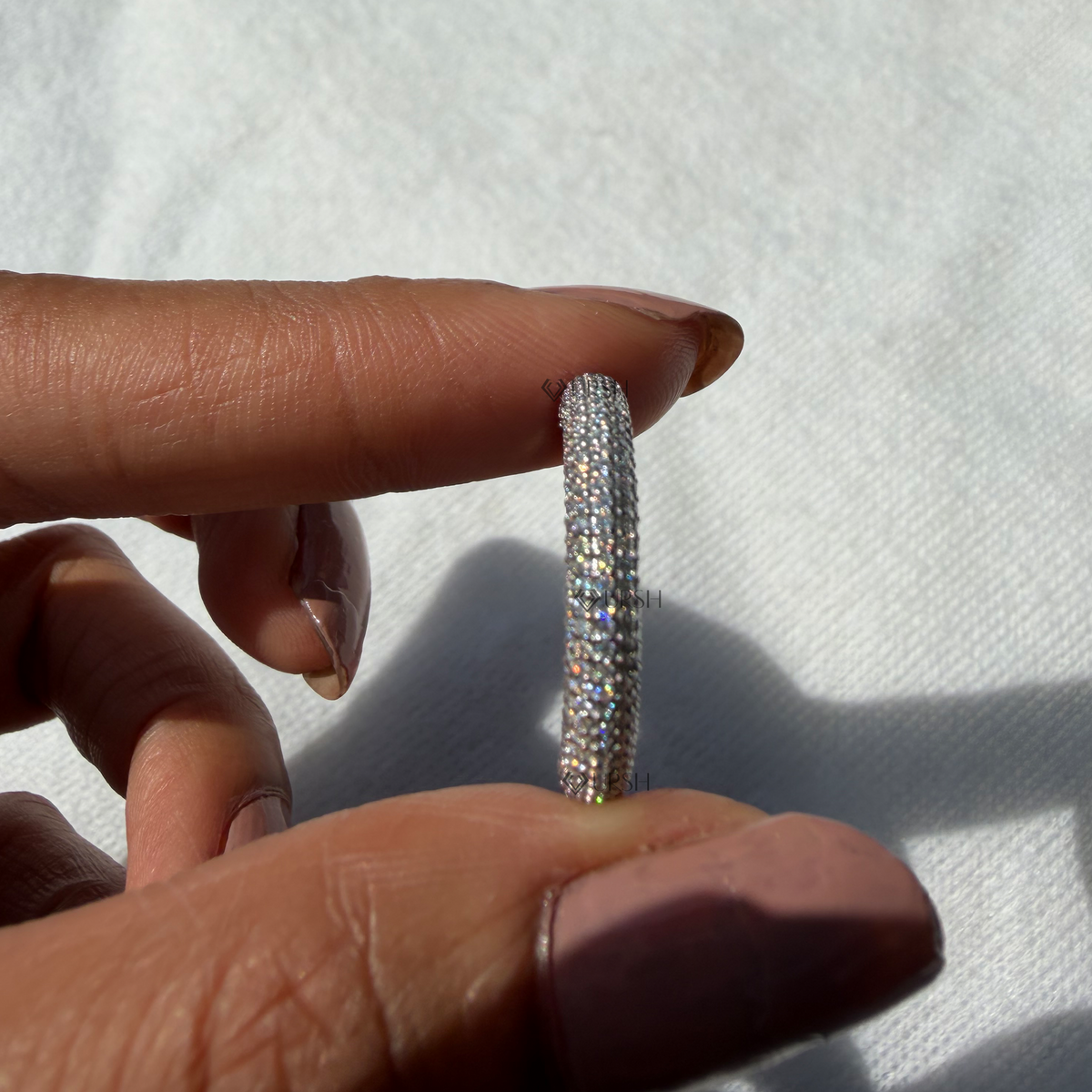 Side profile view of domed pavé diamond ring held between fingertips showcasing curved height