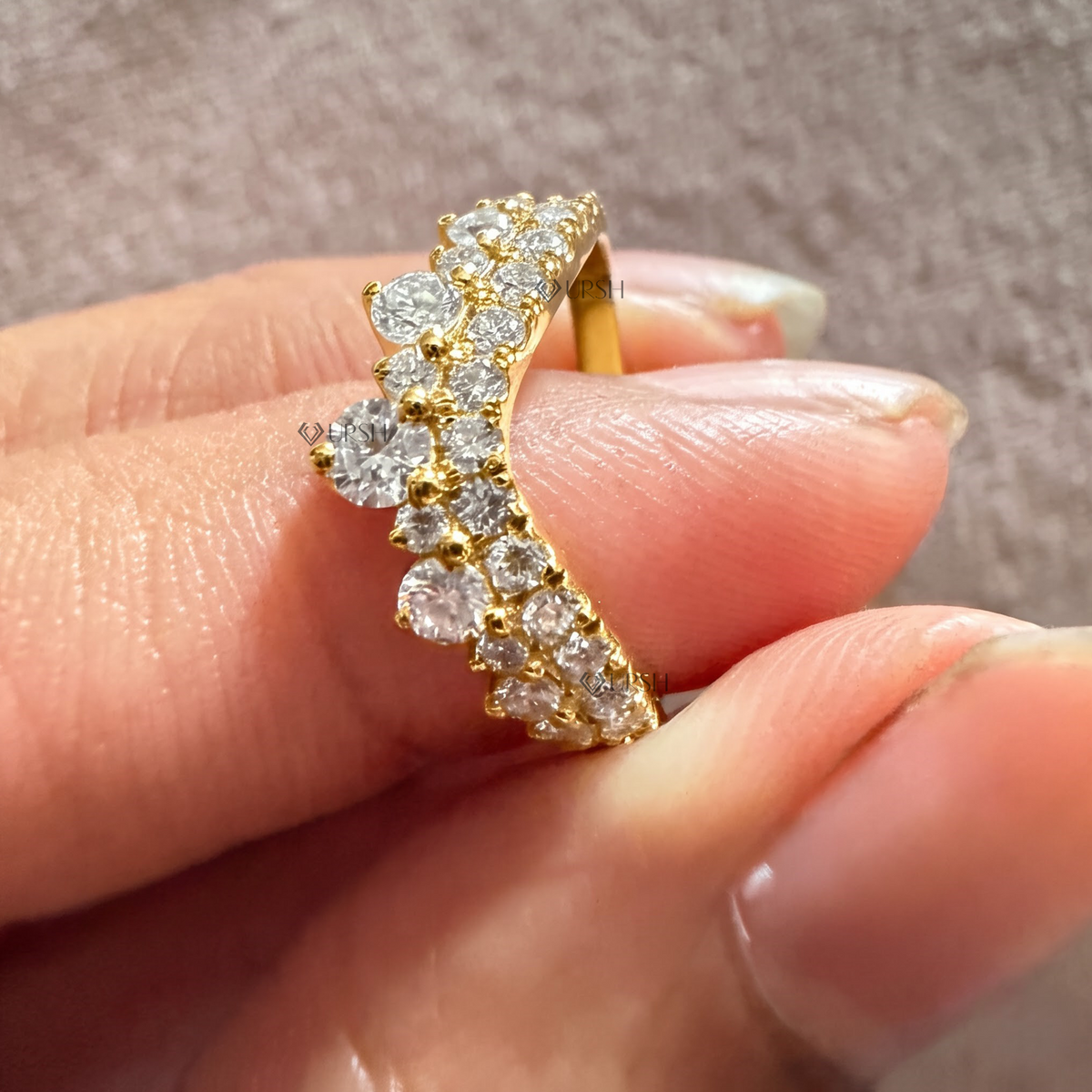 Detailed view of graduated round lab diamonds along the curved V-arc of the crown band