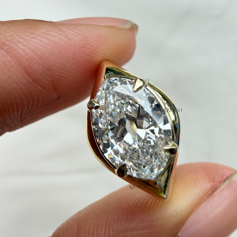 Marquise cut diamond ring with semi-bezel and prong setting being held between fingers