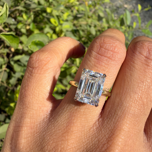 Large emerald cut diamond solitaire catching sunlight on ring finger