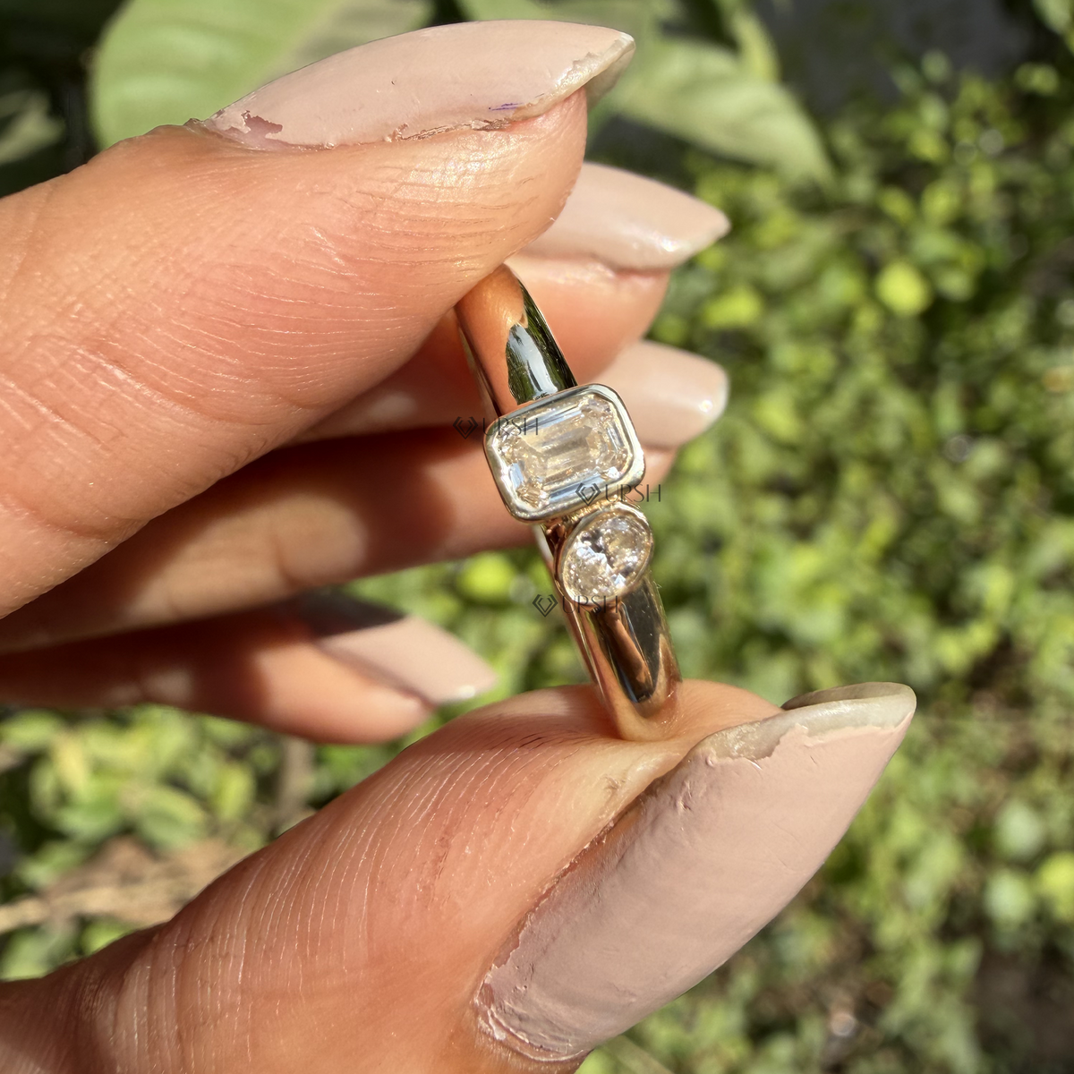 Detailed daylight macro close-up of bezel-set emerald-cut and oval-cut lab diamonds held between fingers