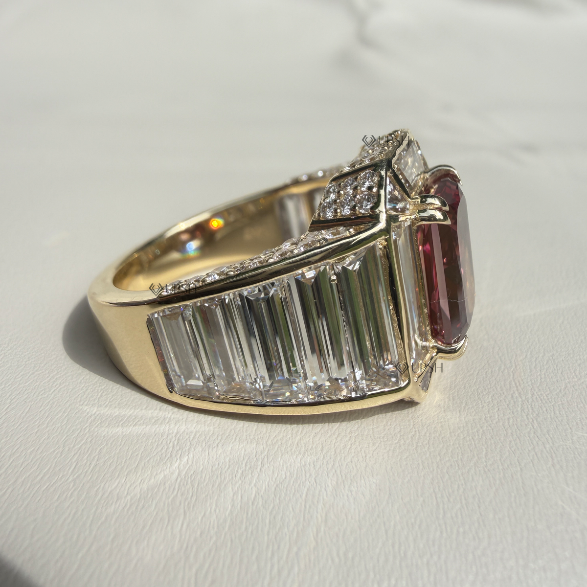Studio angle view of yellow gold ruby ring displaying tiered profile, stacked baguettes, and pavé shoulders