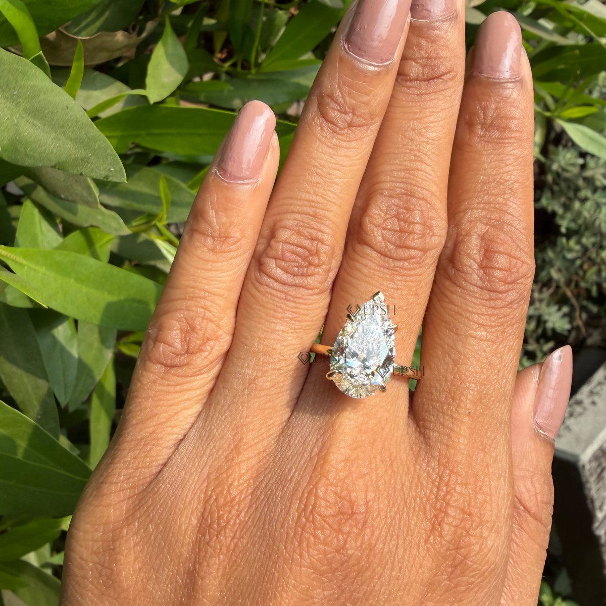 Close-up daylight macro view of giant pear solitaire engagement ring worn on finger