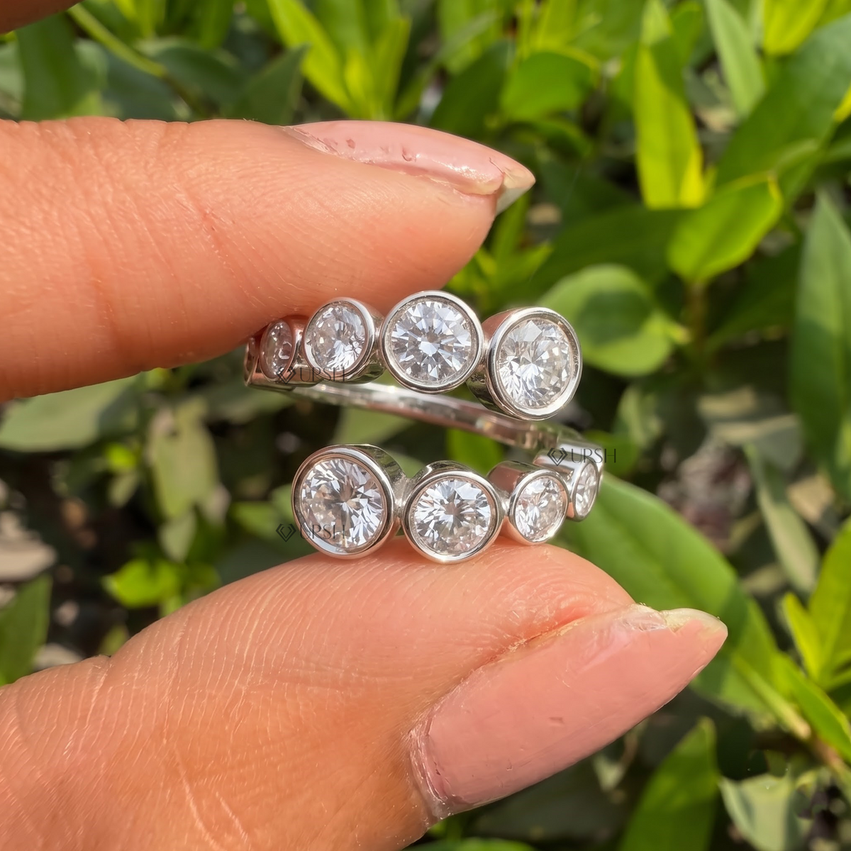 Detailed daylight close-up of graduated round lab diamonds in flush bezel bypass rows worn on hand
