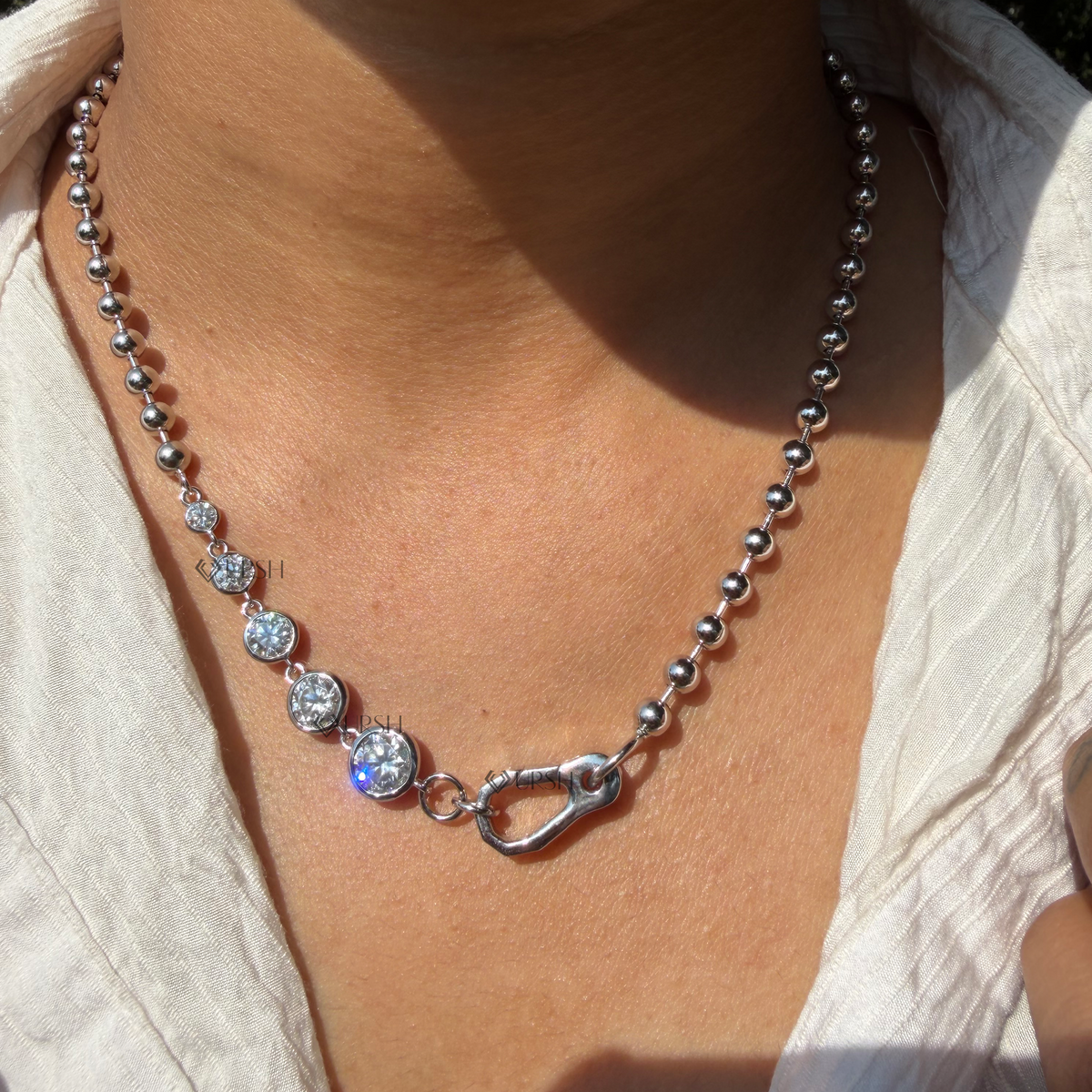 Daylight angle view of white gold graduated diamond ball bead chain with carabiner lock worn on neck