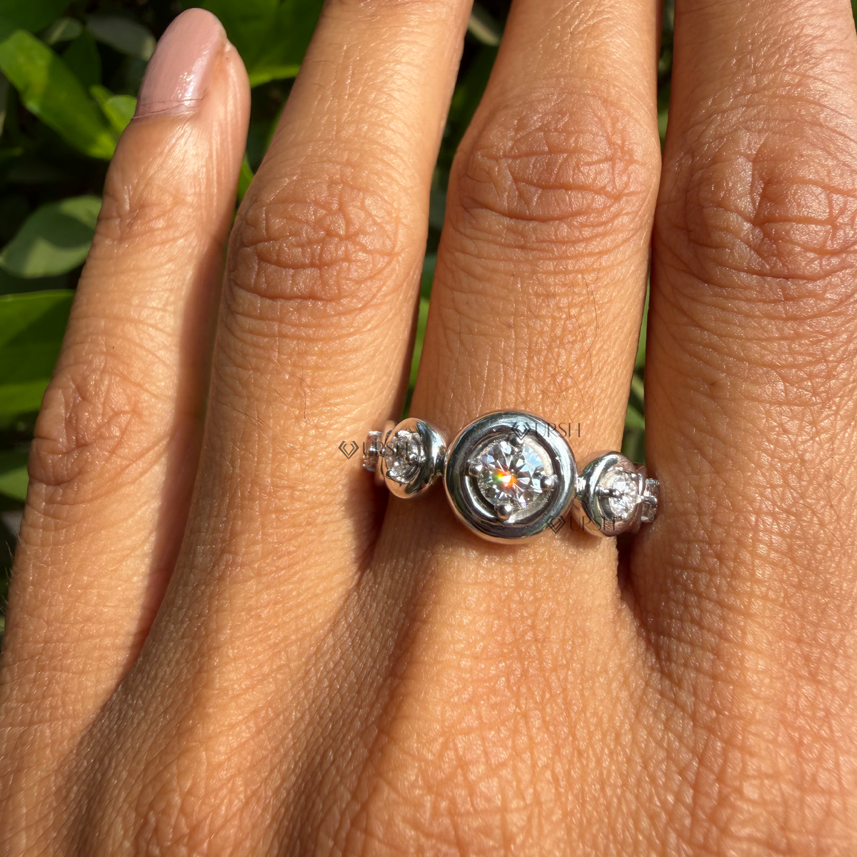 Graduated bezel station diamond ring styled gracefully on finger in natural daylight.
