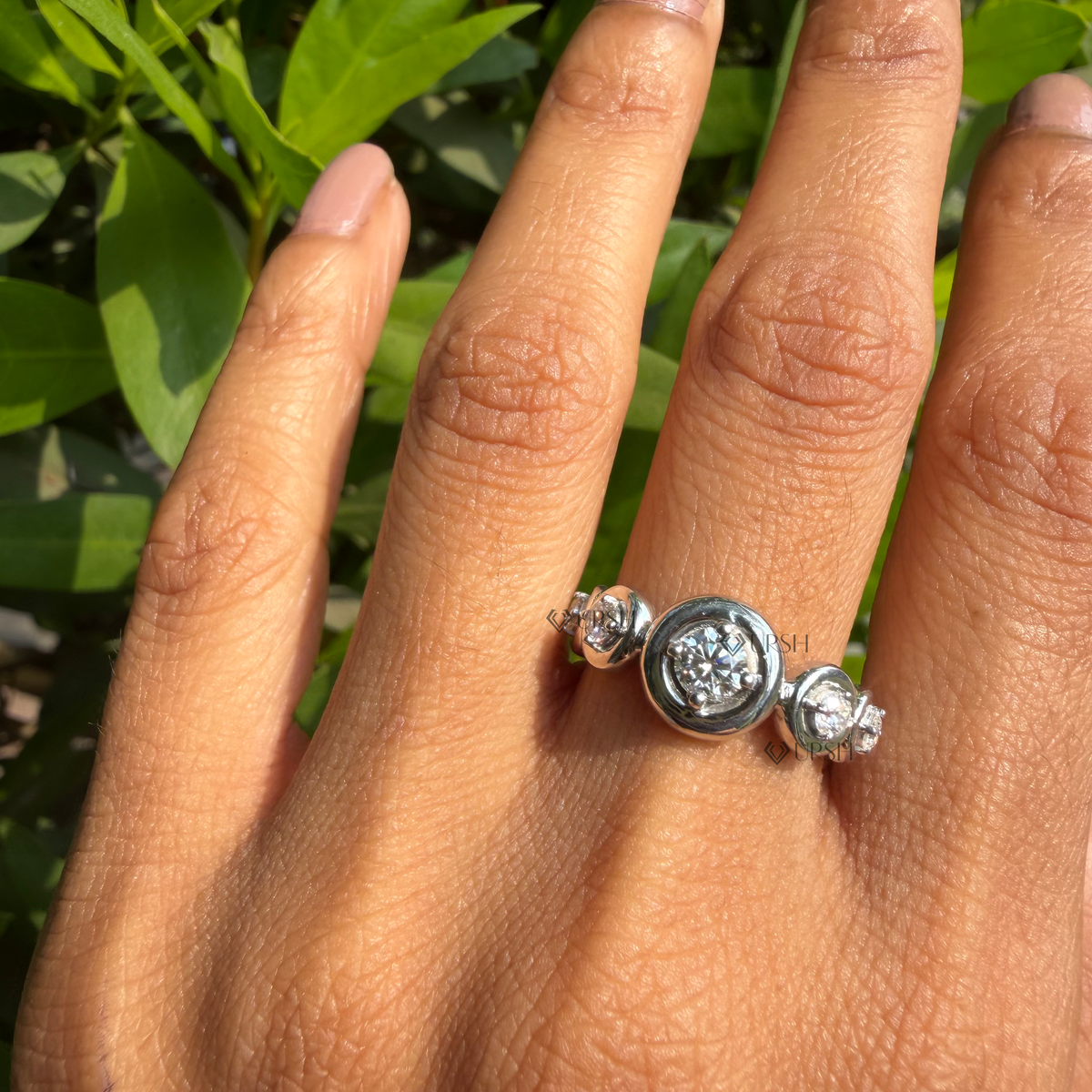 Detailed daylight close-up of graduated round lab diamonds in flush bezel station settings worn on hand.