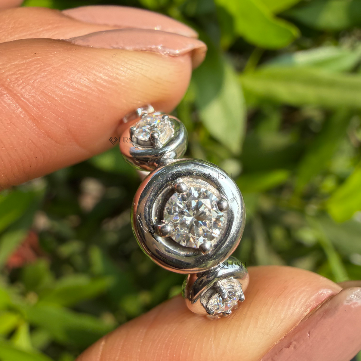Close-up holding solid gold bezel-set station ring highlighting smooth flush bezels and mirror polish.