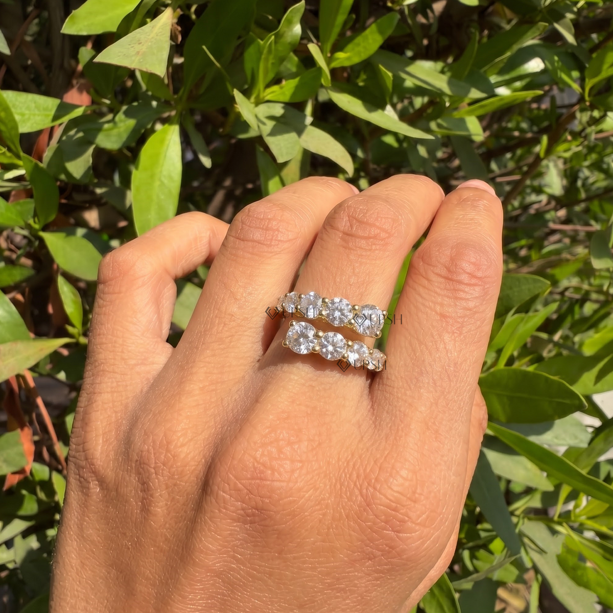 Yellow gold graduated prong bypass ring styled gracefully on finger in natural daylight