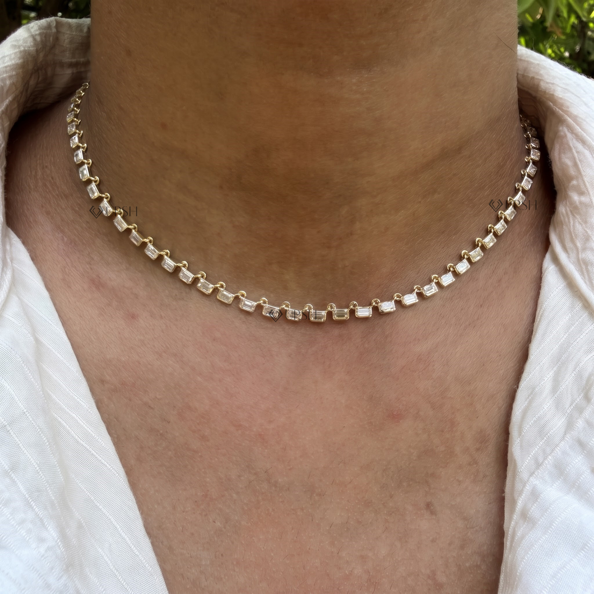 Yellow gold horizontal emerald cut diamond east-west tennis chain necklace styled gracefully on neck in natural daylight
