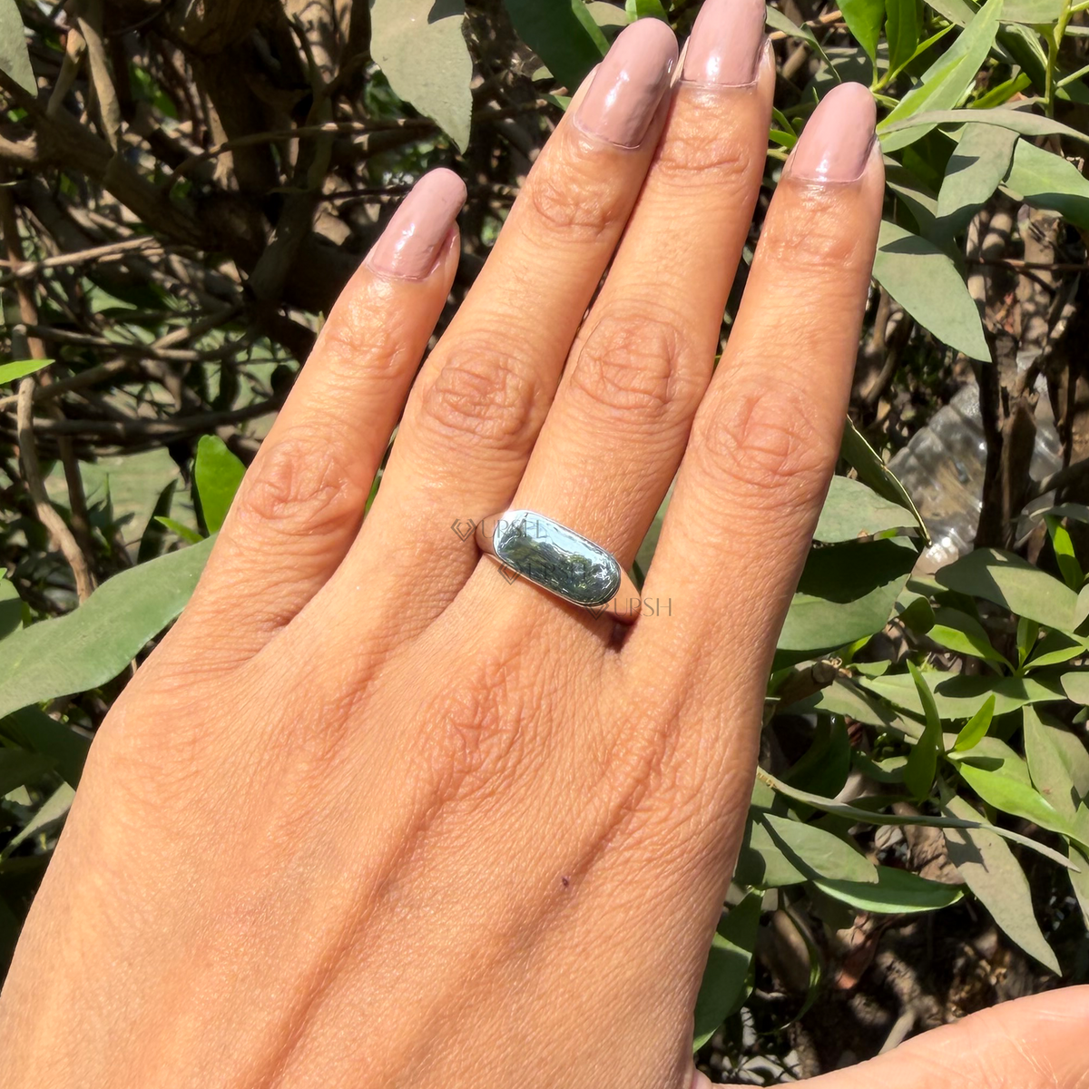 Daylight perspective of white gold oval signet ring worn against natural background