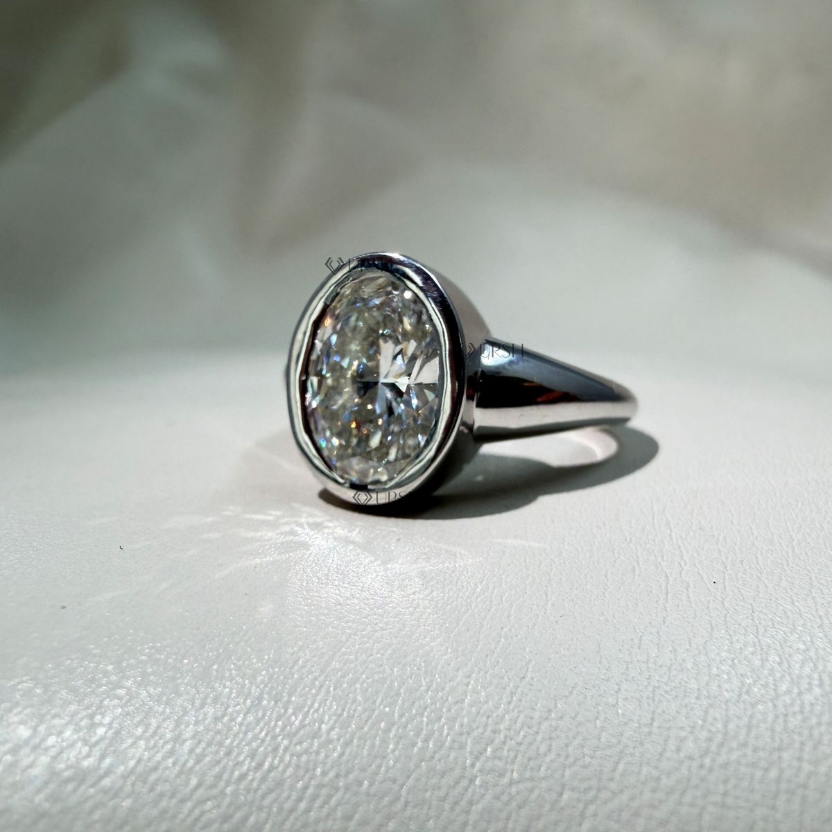 Studio profile view of white gold bezel ring displaying smooth gallery and polished shank curve