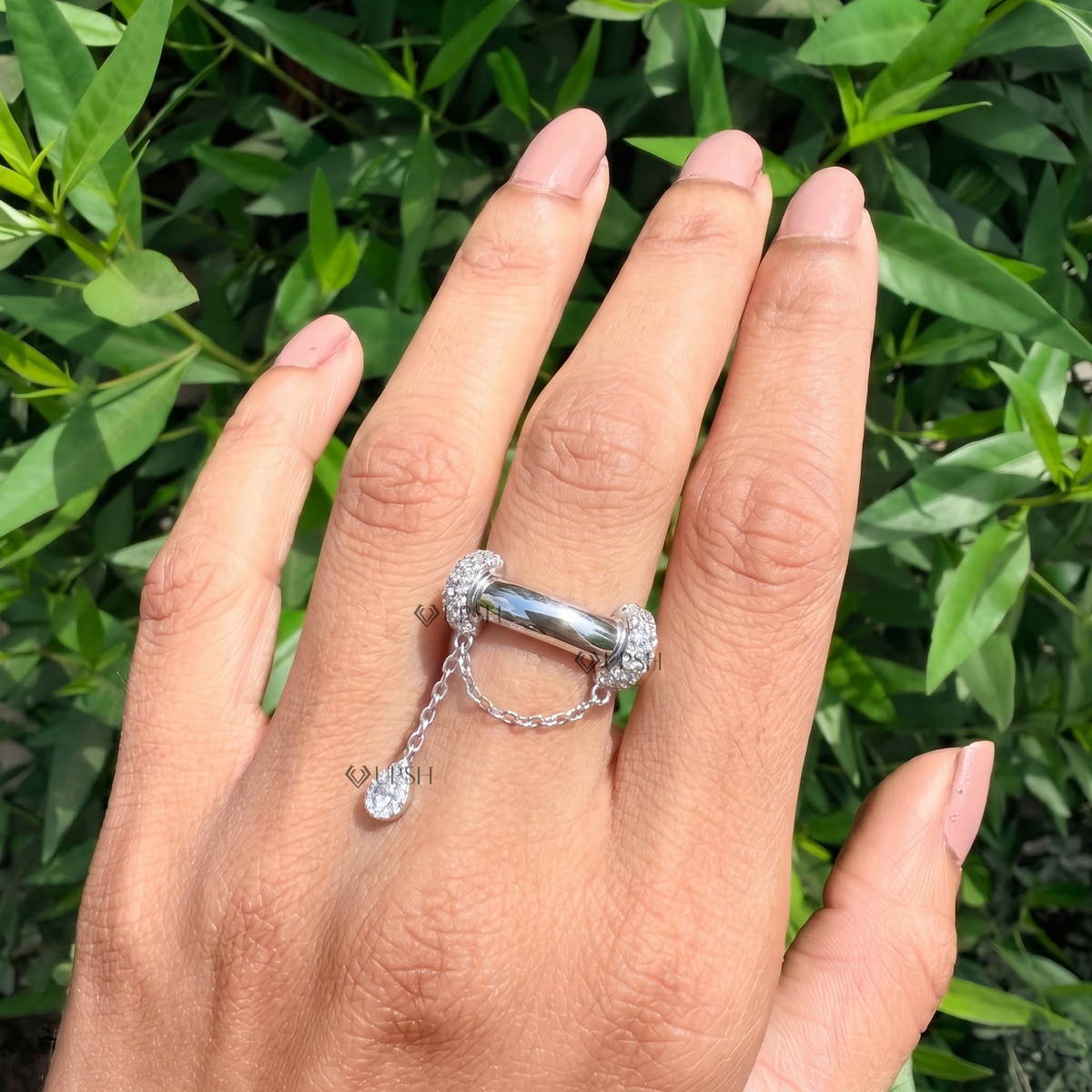 Daylight angle view of white gold dangle chain statement ring worn on hand showcasing unique structural silhouette