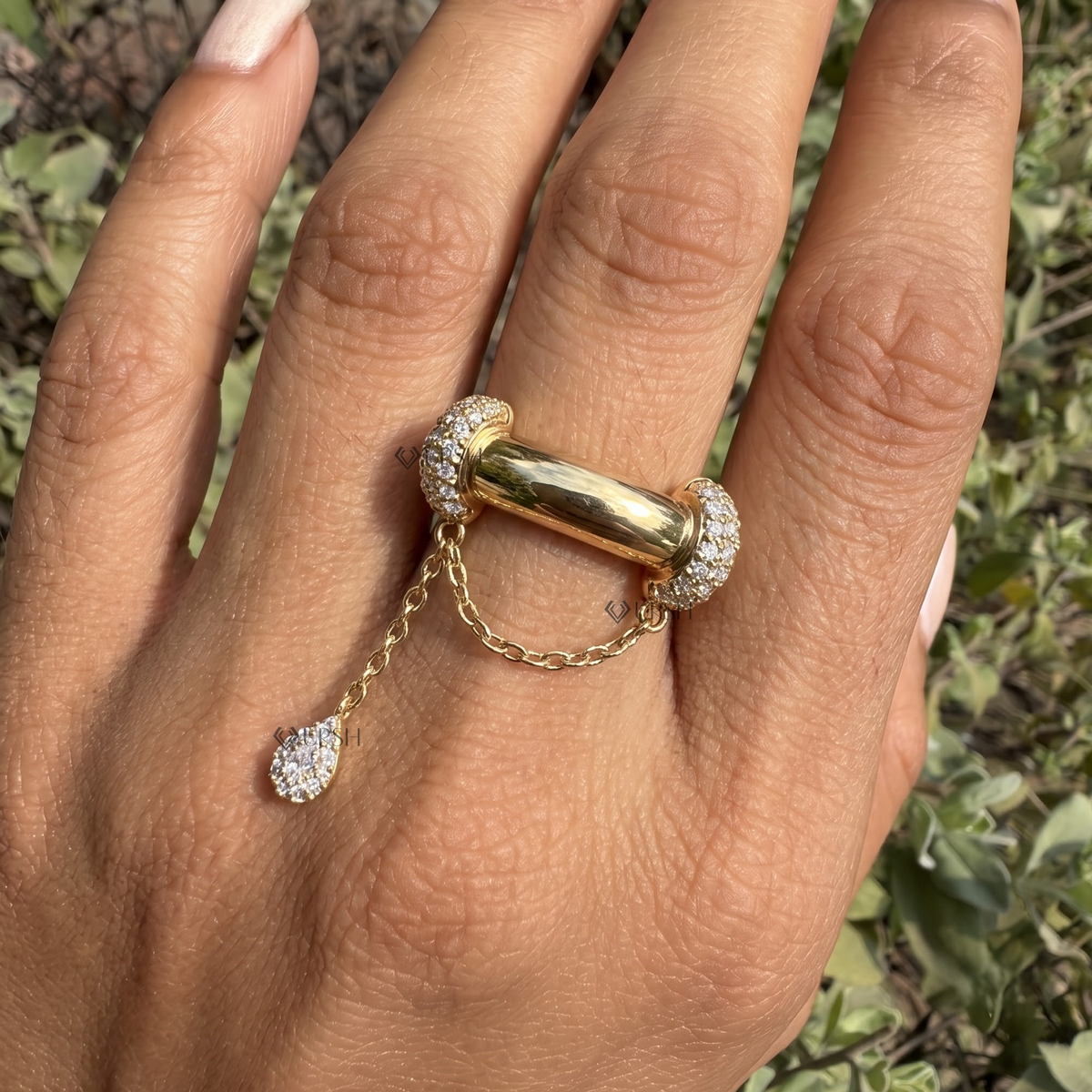 Daylight perspective of pavé diamond chain ring worn against natural garden background