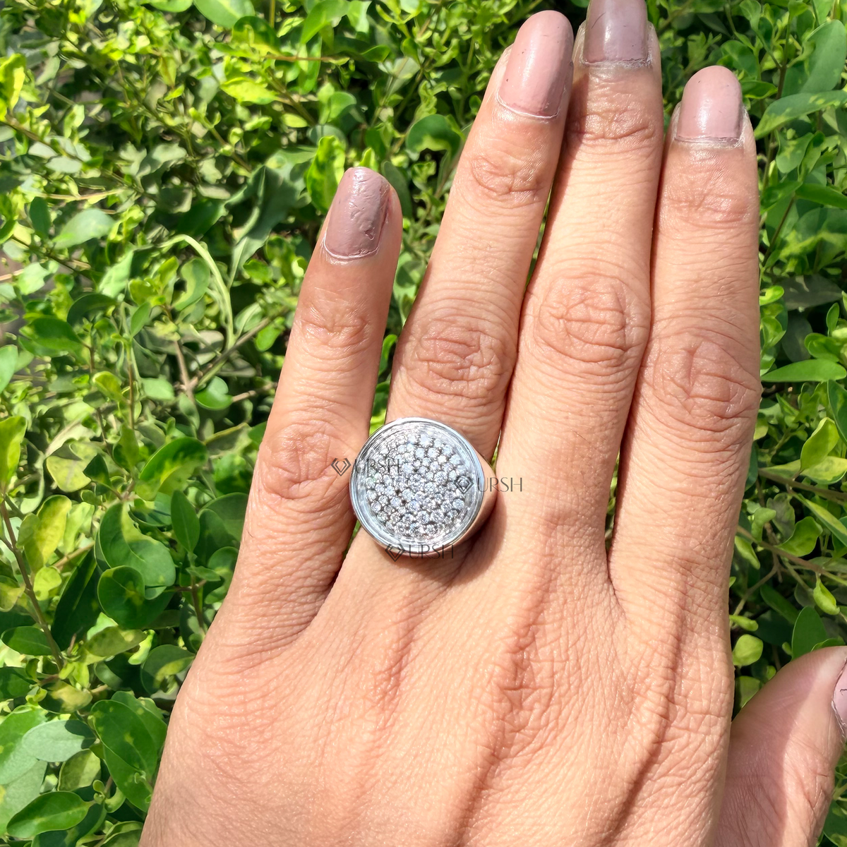 Detailed daylight macro close-up of dense circular pavé diamond disc and mirror bezel worn on finger