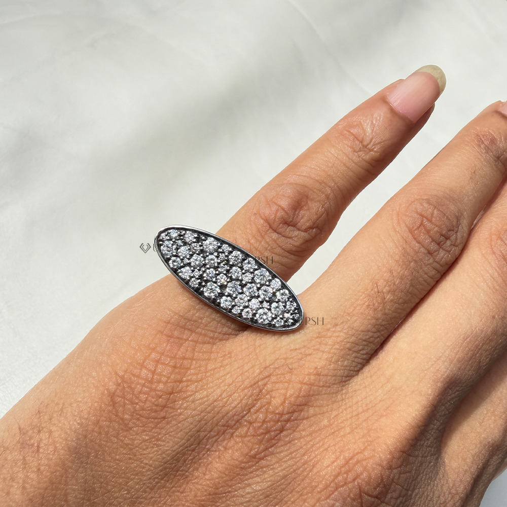 East-west elongated oval diamond shield cocktail ring styled across index finger in daylight