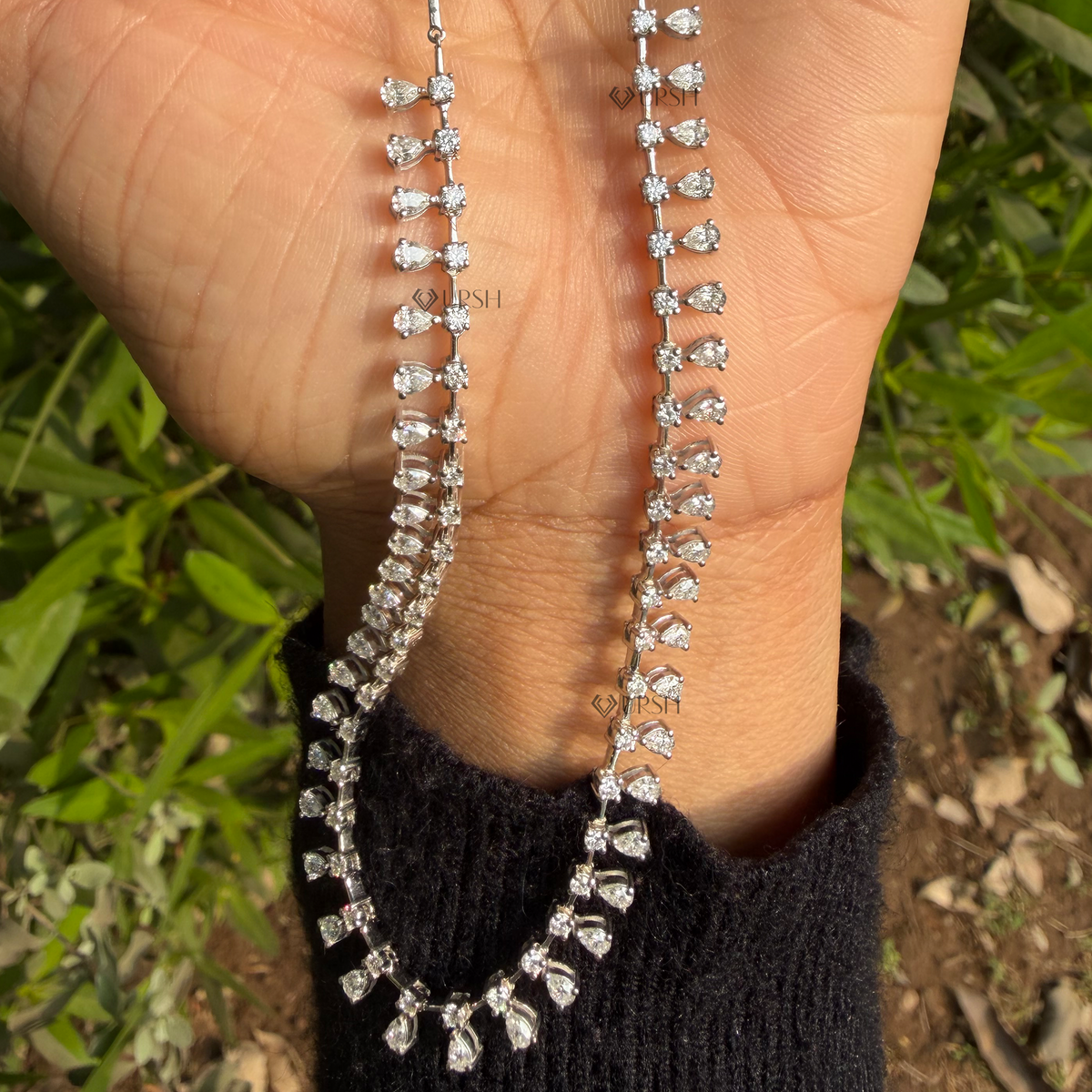 Detailed macro shot of white gold cascading pear diamond drops held gracefully in hand