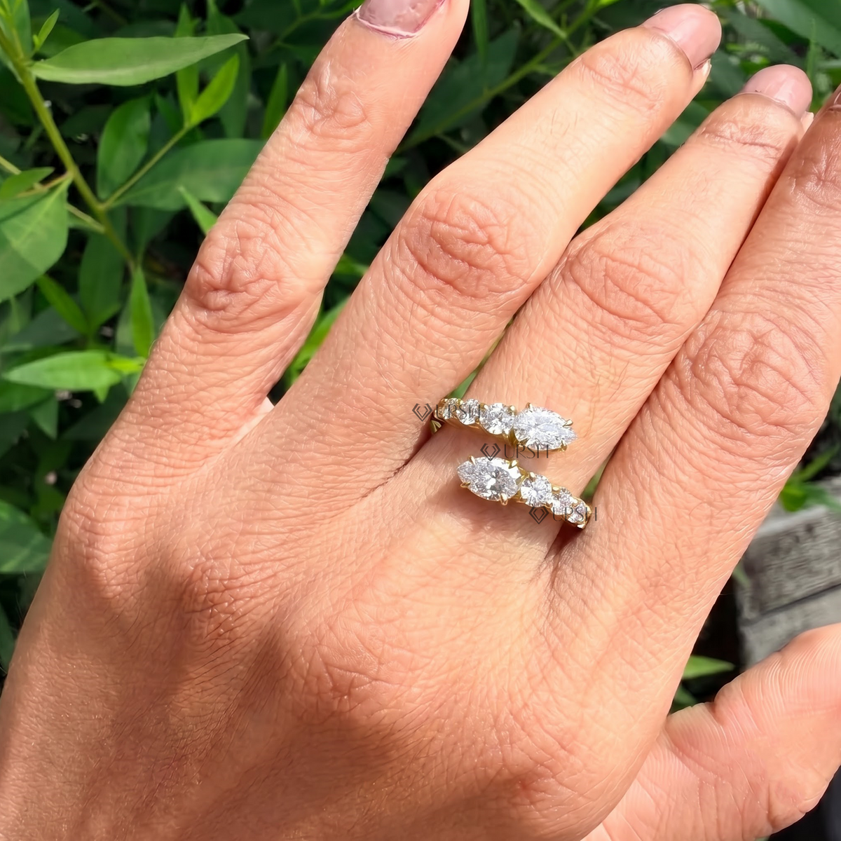 Graduated pear and round diamond bypass ring styled gracefully on finger in natural daylight