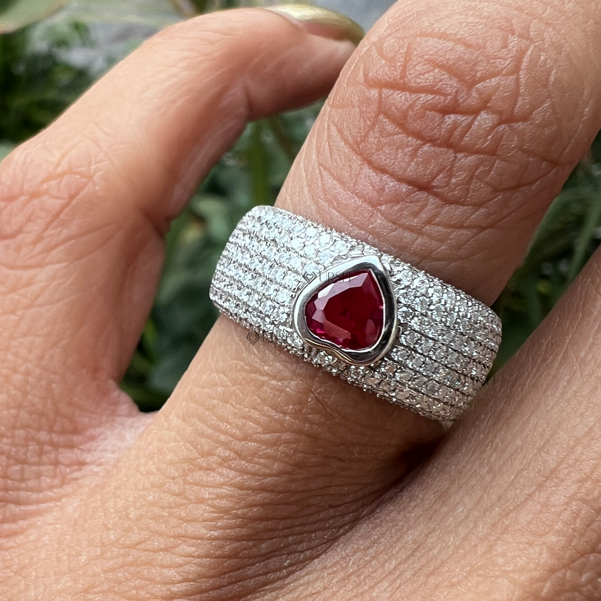 Daylight angle view of white gold heart ruby cigar band ring worn on hand showcasing wide profile