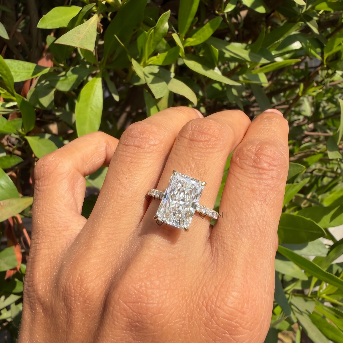Radiant cut diamond engagement ring styled gracefully on finger in natural daylight