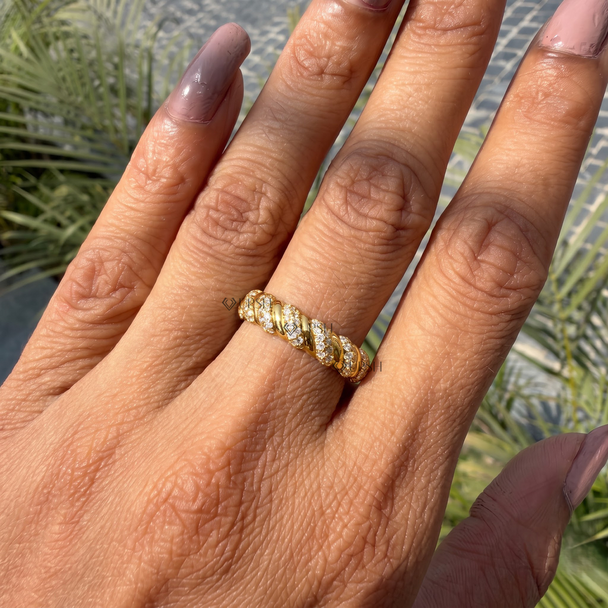 Yellow gold twisted cable diamond stacking band catching sunlight on ring finger