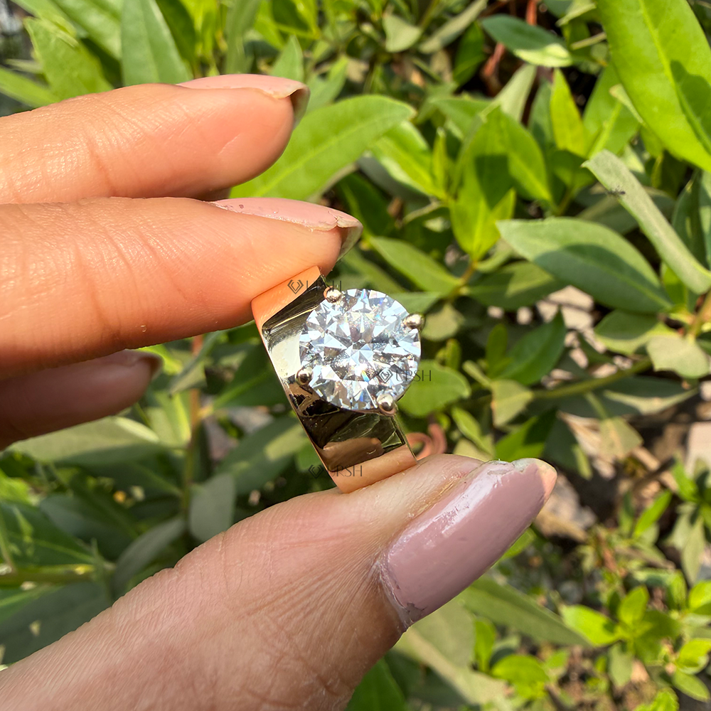 Detailed macro close-up holding solid gold wide cigar band solitaire ring to display mirror finish.