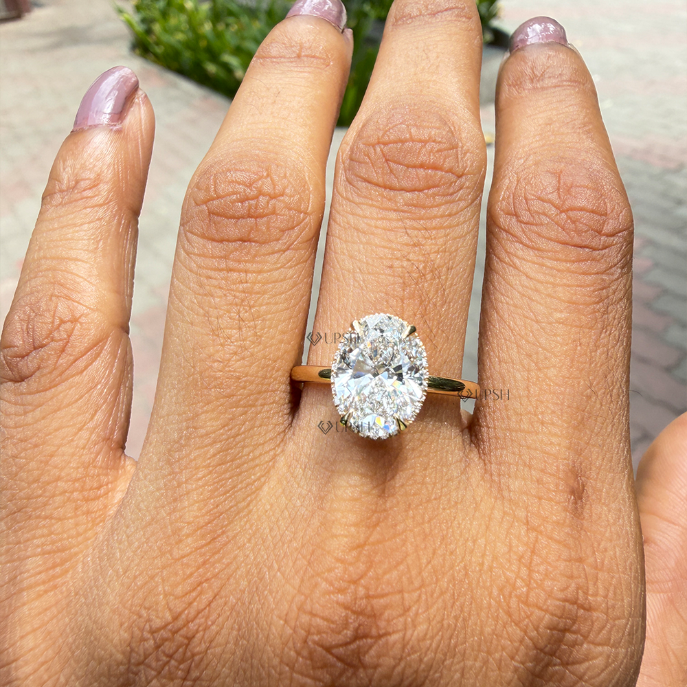 Oval cut lab diamond hidden halo engagement ring worn on hand outdoors