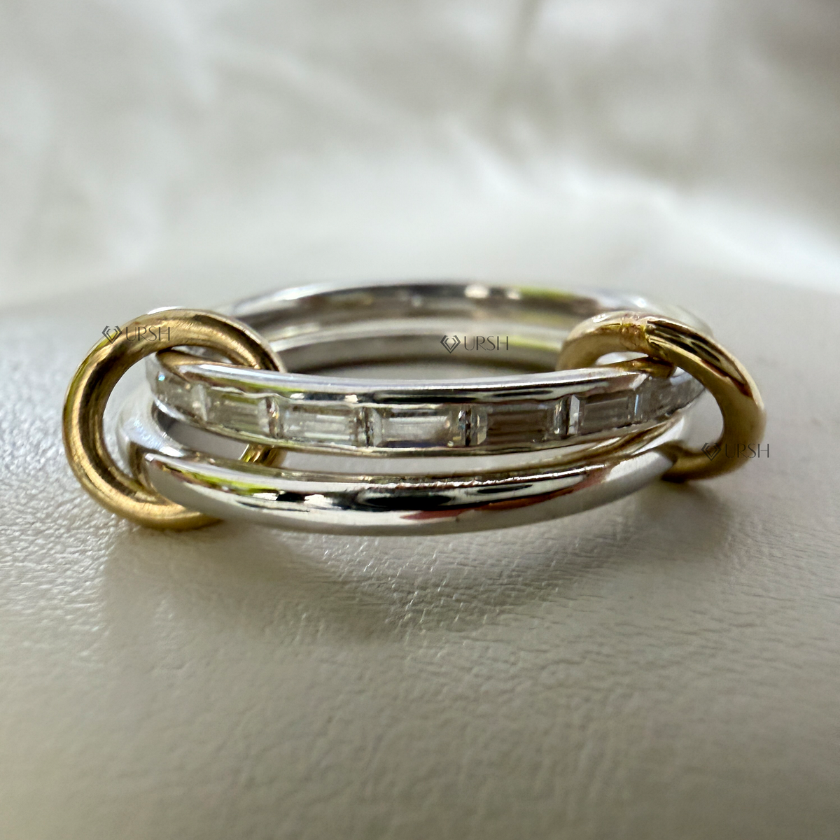 Close-up studio view of interlinked white and yellow gold bands highlighting smooth loop connections