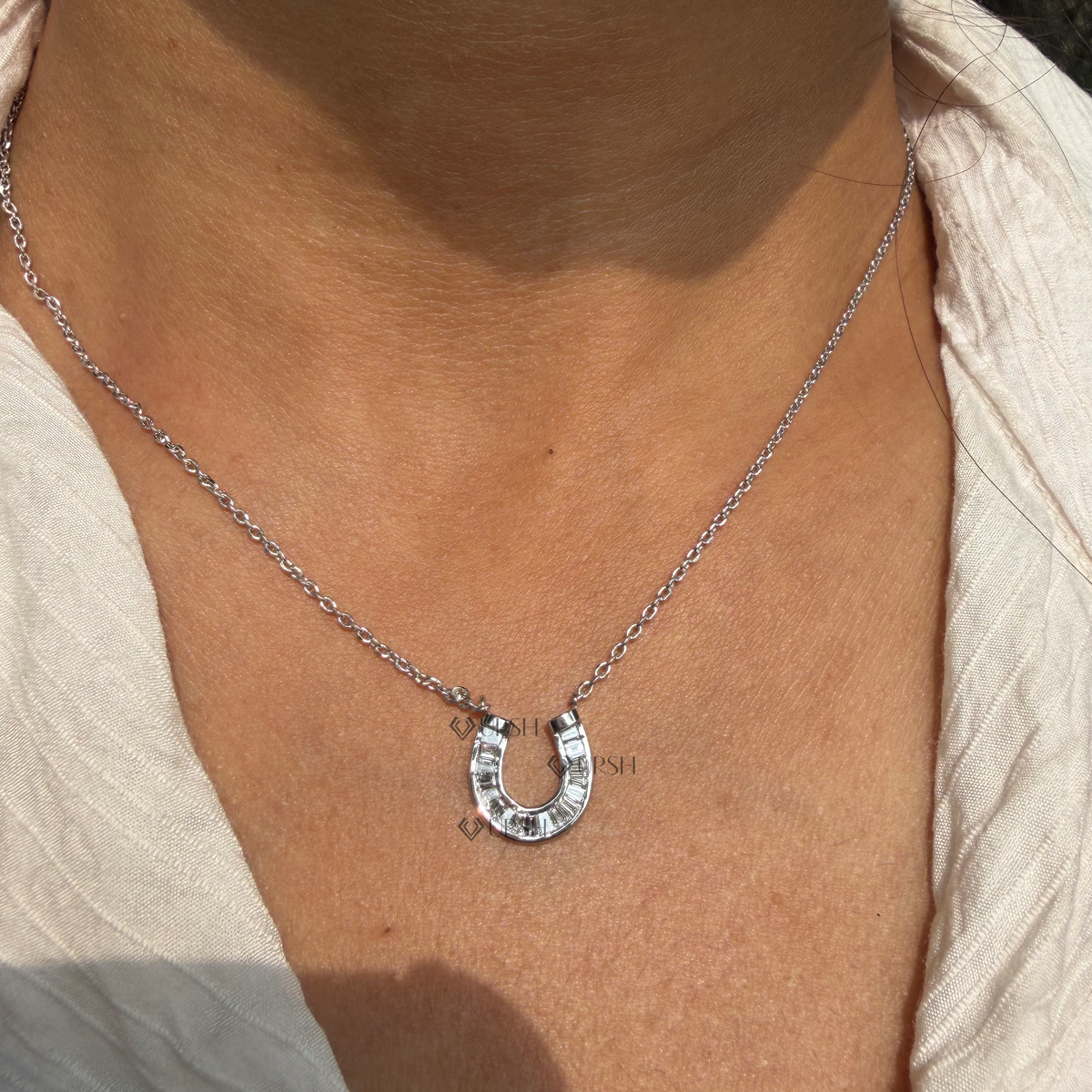Daylight angle view of white gold horseshoe diamond pendant necklace resting along collarbone
