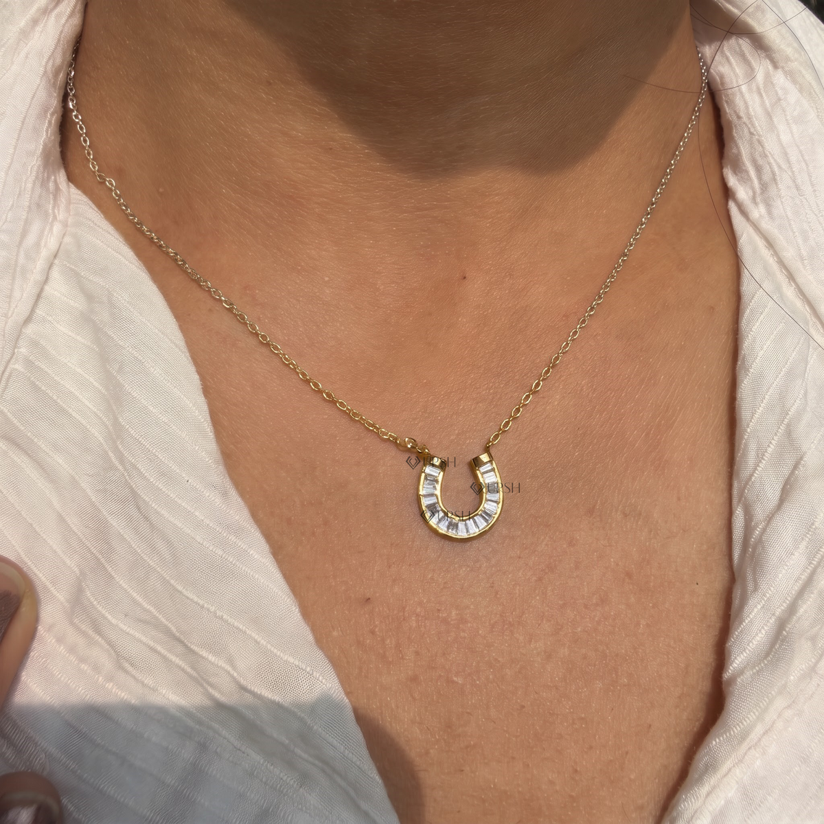 Yellow gold baguette diamond horseshoe pendant necklace styled gracefully on neck in natural daylight