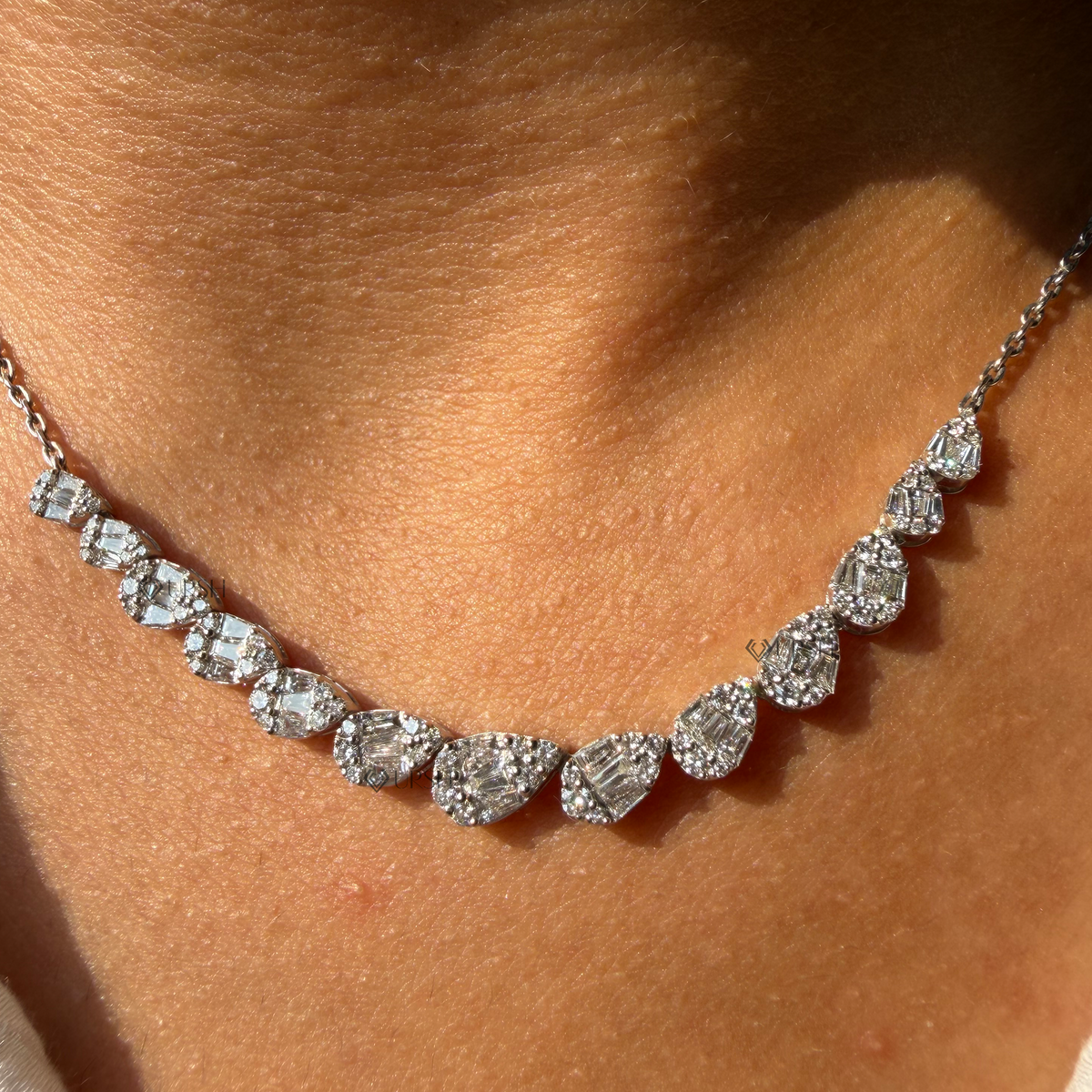 Daylight perspective view of yellow gold graduated pear-shaped cluster diamond frontage chain worn along collarbone