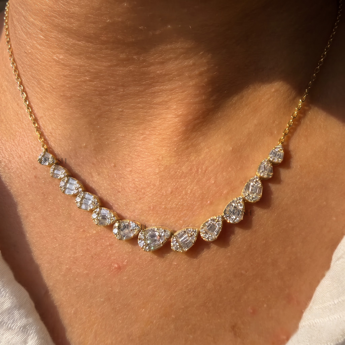 Yellow gold graduated pear cluster diamond station frontage necklace styled gracefully on neck in natural daylight