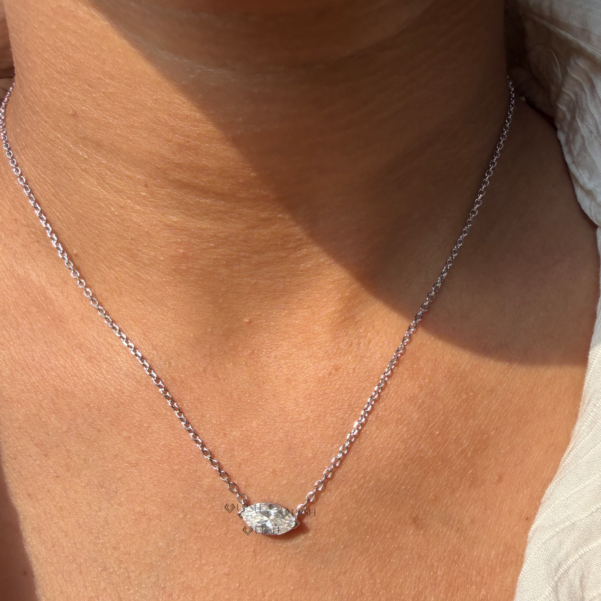 Daylight perspective of yellow gold east-west marquise diamond solitaire pendant worn along collarbone