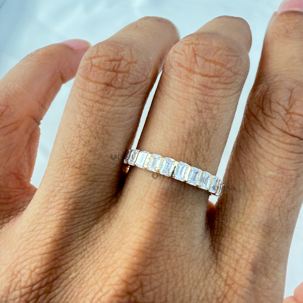 Emerald cut diamond bar set wedding band worn on ring finger in natural lighting