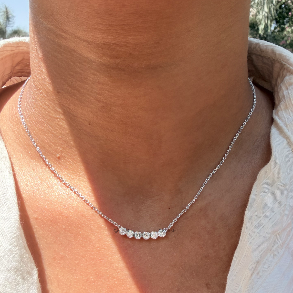 Daylight perspective view of white gold round diamond smile bar pendant necklace worn on collarbone